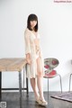 A woman standing in front of a wooden table.