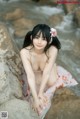 A woman sitting on a rock by the water.