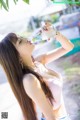 A woman in a pink top drinking from a bottle.