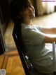 A woman sitting on a chair in front of a window.