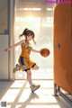 A girl in a yellow and blue uniform holding a basketball.