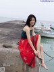 A woman sitting on a concrete wall next to a body of water.