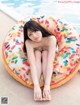 A woman sitting on an inflatable donut by a swimming pool.