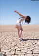 A woman standing in the middle of a dry, cracked ground.